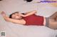A woman laying on top of a bed in a red top.