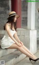 A woman in a white dress and a straw hat sitting on some steps.