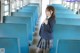 A woman in a school uniform standing in a train.