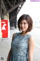 A woman in a blue dress standing on a sidewalk.