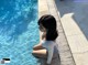 A woman sitting on the edge of a swimming pool.