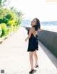 A woman in a black dress standing on a sidewalk.